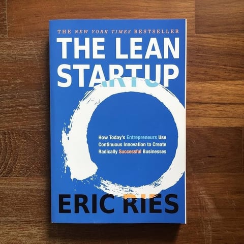 The Lean Startup book by Eric Ries on wooden surface, New York Times bestseller with blue cover and white circle design